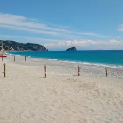 Plage de sable et de galets à Spotorno, Italie. Deux canots de sauvetage rouges sont prêts sur le sable, face à la mer bleue.