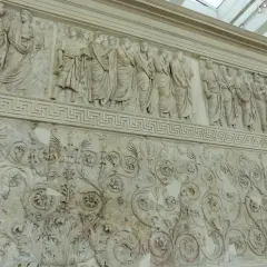 Bas-reliefs de l'Ara Pacis à Rome, représentant des figures toges et des motifs floraux complexes.