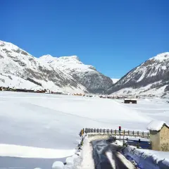 Paysage hivernal à Livigno, Italie. Montagnes enneigées, village pittoresque et route dégagée sous un ciel bleu éclatant.