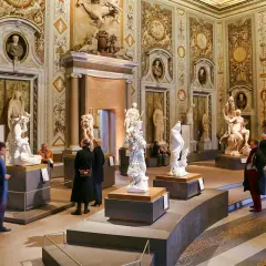 Salle ornée de sculptures classiques à la Villa Borghese. Des visiteurs admirent des œuvres d'art dans un décor somptueux.