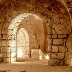 Intérieur voûté des catacombes Saint-Calixte, éclairé par des lumières douces, révélant des murs de pierres anciennes et un sarcophage orné.