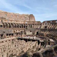 Vue intérieure du Colisée de Rome, vestiges de l'arène et des gradins, avec des touristes explorant ce monument historique.