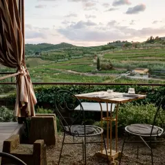 Terrasse d'agroturismo en Sicile avec vue sur les vignobles et les oliviers. Table dressée pour deux, prête pour un dîner paisible.