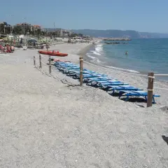 Plage de Loano, Italie, avec des chaises longues bleues alignées près de la mer Méditerranée.