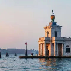 La Dogana di Venezia, un bâtiment historique, se dresse au bord de l'eau. Un couple s'embrasse près d'un lampadaire.
