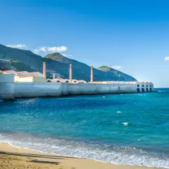 Ancienne conserverie de thon à Favignana, Sicile, avec ses cheminées emblématiques se dressant face à la mer turquoise.