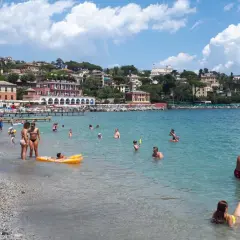 Journée ensoleillée à la plage Santa Margherita Ligure, baigneurs profitant de la mer turquoise et des bâtiments colorés en arrière-plan.