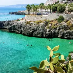 Plage rocheuse et eaux turquoise à Castro, Italie. Des baigneurs profitent du soleil et de la mer.