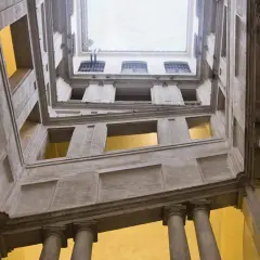Vue en contre-plongée de l'escalier monumental du Palazzo Barberini, avec ses colonnes imposantes et ses fenêtres lumineuses.
