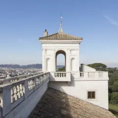Vue panoramique de Rome depuis la Villa Médicis. Un belvédère blanc orné d'une arche domine le paysage urbain.