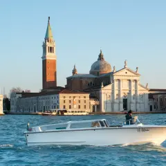 Taxi boat naviguant sur le Grand Canal, avec l'église San Giorgio Maggiore en arrière-plan. Idéal pour connaître le tarif taxi Venise.