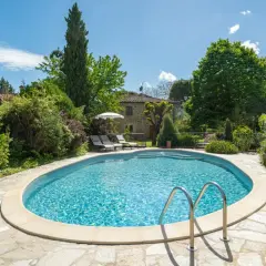 Magnifique piscine dans un jardin luxuriant, typique d'une location en Toscane. Le soleil brille sur l'eau bleue, invitant à la détente.