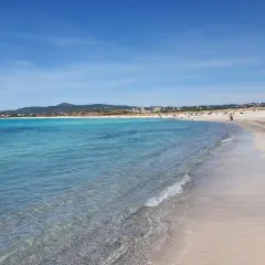 Plage de sable fin à Vada, eaux turquoise, ciel bleu, quelques personnes profitent du soleil.