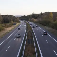 Voiture circulant en Italie sur une autoroute bordée d'arbres aux couleurs d'automne.