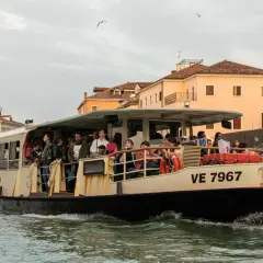 Un passager sur un vaporetto à Venise, naviguant sur les canaux bordés de bâtiments historiques.