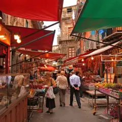 Ambiance animée au marché de la Vucciria à Palerme, avec des étals colorés, des fruits frais et des boucheries.