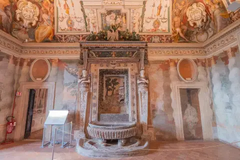 Intérieur de la Villa d'Este : une fontaine ornée de sculptures et de fresques murales dépeignant des scènes mythologiques et des paysages.