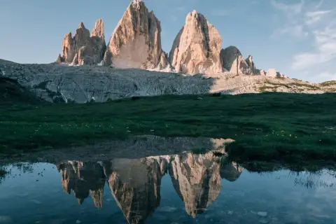 Les Trois Cimes de Lavaredo se reflètent dans un étang près de Misurina, sous un ciel bleu clair.