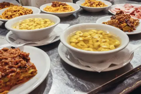 Un festin de pâtes et de charcuterie dans un restaurant de Bologne. Lasagnes, tortellinis en bouillon, tagliatelles à la bolognaise et assiette de jambons.
