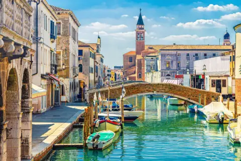 Un rêve d'aller à Venise : un canal bordé de maisons anciennes, un pont de briques et des gondoles.