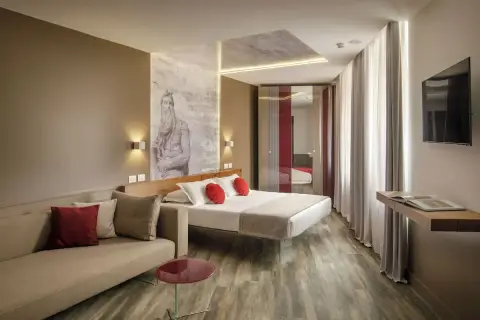 Chambre moderne avec un lit, un canapé et une œuvre d'art murale inspirée de Michel-Ange, typique du **hotel Regno Rome**.