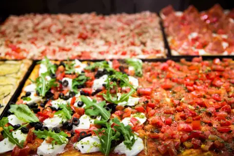 Des pizzas romaines rectangulaires appétissantes, dont une à la mozzarella fraîche, olives et roquette, la meilleure pizza Rome.