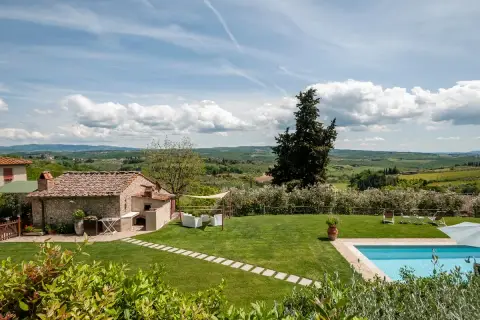 Magnifique vue sur des gîtes en Toscane avec piscine, jardin verdoyant et paysage vallonné sous un ciel bleu.