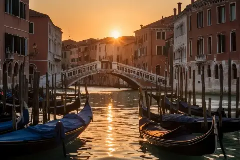 Gondoles amarrées sur un canal vénitien au coucher du soleil, avec un pont en arrière-plan.