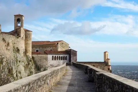 Chemin de pierre menant à un ancien château avec clocher, surplombant une ville en contrebas, typique de la massa italie.