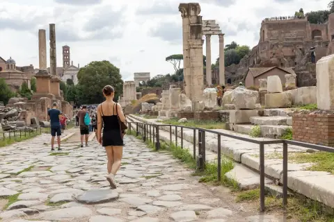 Une femme se promène sur une voie pavée dans le Forum romain, un site idéal pour visiter Rome en 4 jours.