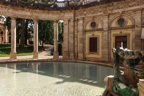 Fontaine sculptée d'un dragon à Montecatini, avec une arcade de colonnes en arrière-plan et un bassin d'eau claire.