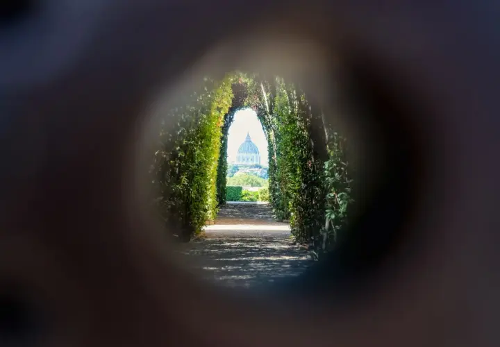 Un chemin bordé de verdure mène à la coupole de Saint-Pierre, une vision de Rome insolite et secrète à travers un trou de serrure.