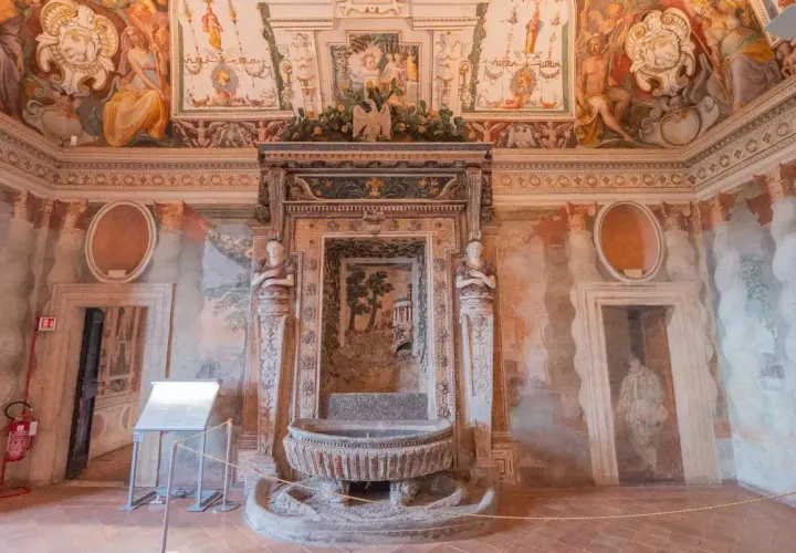 Intérieur de la Villa d'Este : une fontaine ornée de sculptures et de fresques murales dépeignant des scènes mythologiques et des paysages.