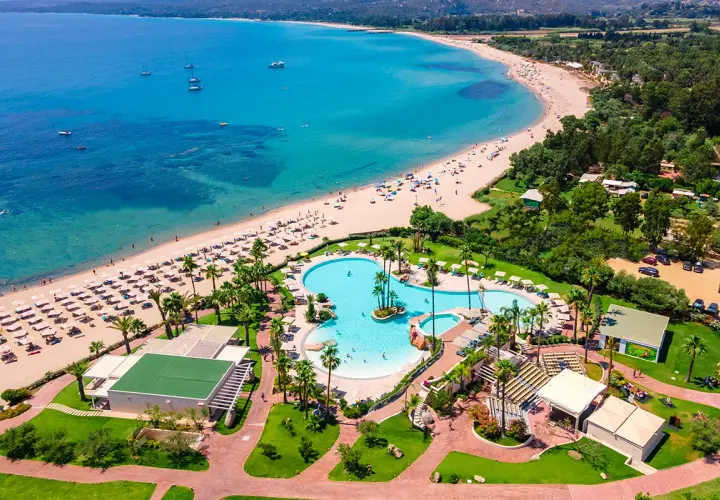 Vue aérienne du **hôtel club Saraceno** avec sa plage de sable fin, sa mer turquoise et sa piscine spectaculaire.