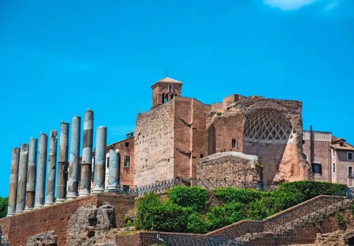Vestiges de la Domus Aurea, avec ses colonnes antiques et ses ruines de briques sous un ciel bleu éclatant.