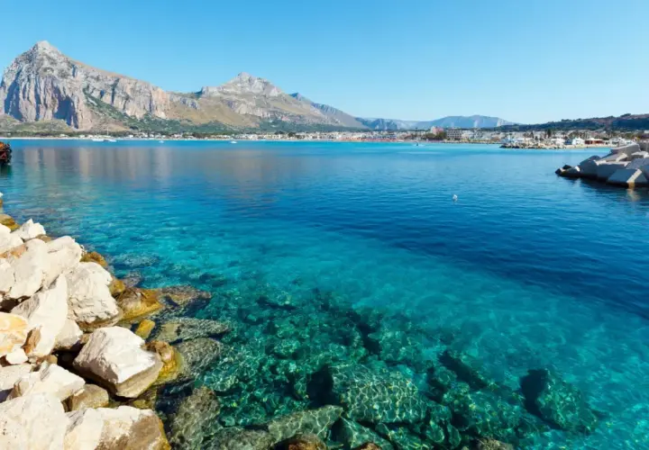 Vue sur la mer turquoise et les montagnes de Capo San Vito. Des rochers blancs bordent la côte.