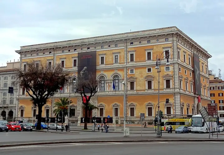 Le **Palazzo Massimo alle Terme**, un édifice majestueux, se dresse fièrement, orné d'une bannière publicitaire.
