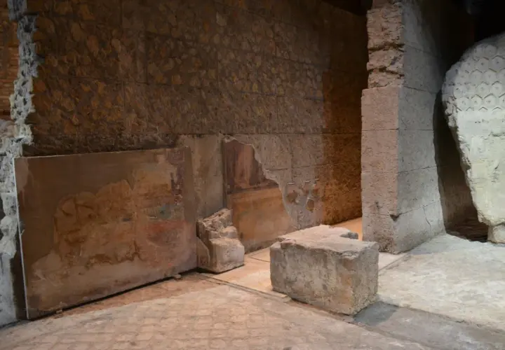Vestiges d'une fresque murale dans la maison d'Auguste à Rome, avec des blocs de pierre et des murs en ruine.
