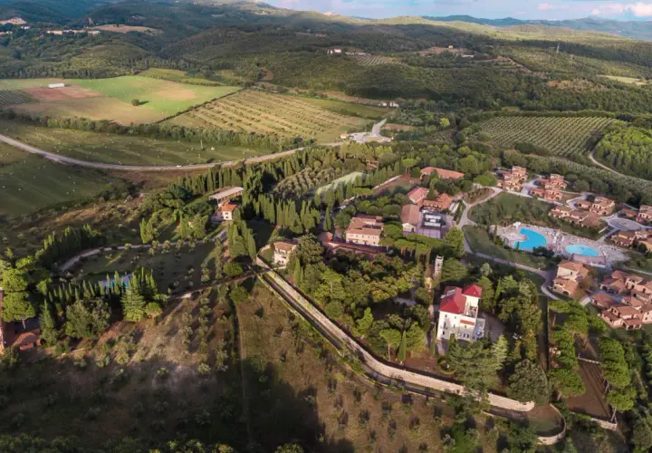 Vue aérienne du Pian dei Mucini, un domaine toscan avec des villas, des cyprès et une piscine.