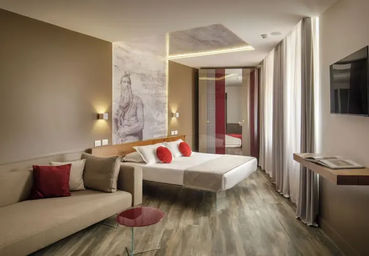 Chambre moderne avec un lit, un canapé et une œuvre d'art murale inspirée de Michel-Ange, typique du **hotel Regno Rome**.