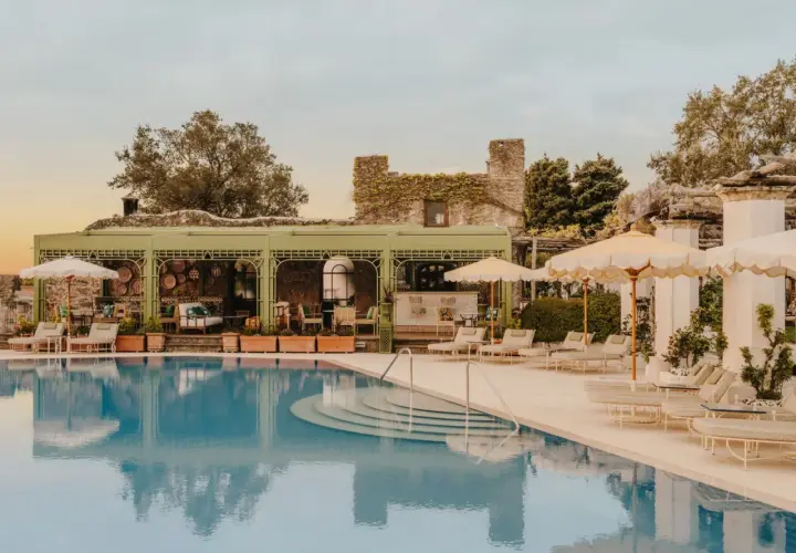 Piscine d'un hôtel club sur la côte amalfitaine, avec des chaises longues, des parasols et un bar extérieur.