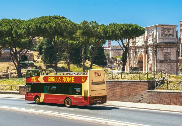 Un bus touristique rouge et jaune circule près de l'Arc de Constantin. Le Vatican n'est pas loin, offrant une vue sur Rome.