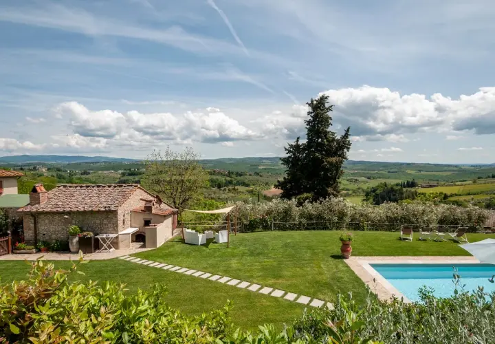 Magnifique vue sur des gîtes en Toscane avec piscine, jardin verdoyant et paysage vallonné sous un ciel bleu.