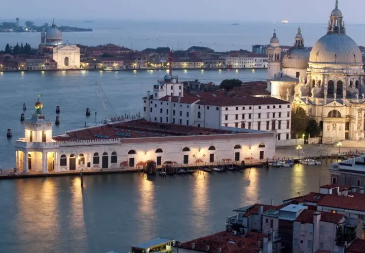 Vue de Venise au crépuscule, avec la basilique Santa Maria della Salute et le bâtiment de la Fondation Pinault Venise illuminés.