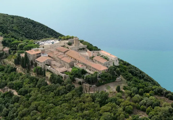 Vue aérienne de Populonia, Italie, un village médiéval perché sur une colline verdoyante surplombant la mer d'un bleu profond.