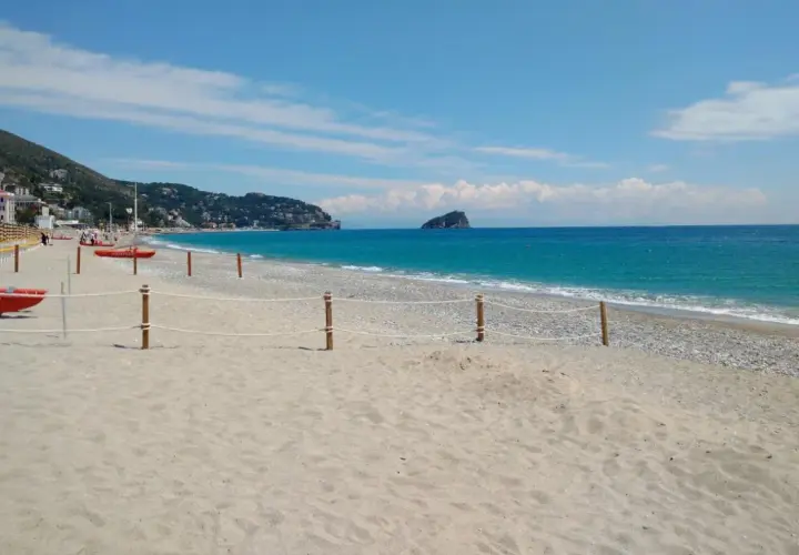 Plage de sable et de galets à Spotorno, Italie. Deux canots de sauvetage rouges sont prêts sur le sable, face à la mer bleue.