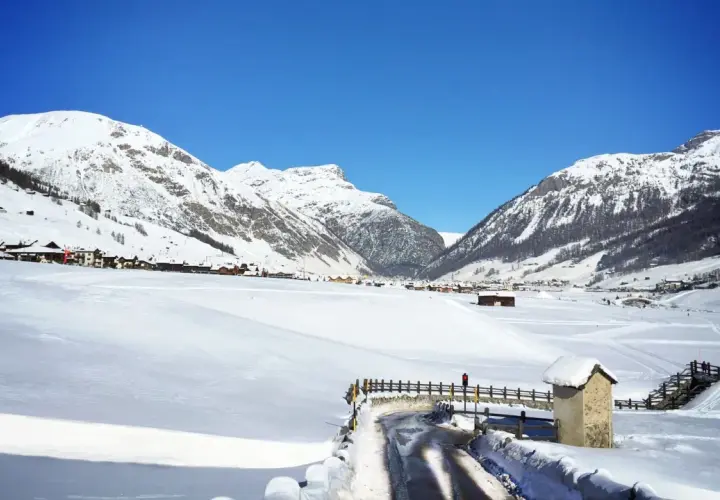Paysage hivernal à Livigno, Italie. Montagnes enneigées, village pittoresque et route dégagée sous un ciel bleu éclatant.