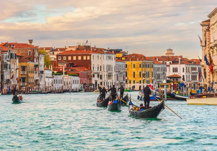 Gondoles glissant sur le Grand Canal, un jour d'octobre à Venise. Les façades colorées des palais se reflètent dans l'eau calme.