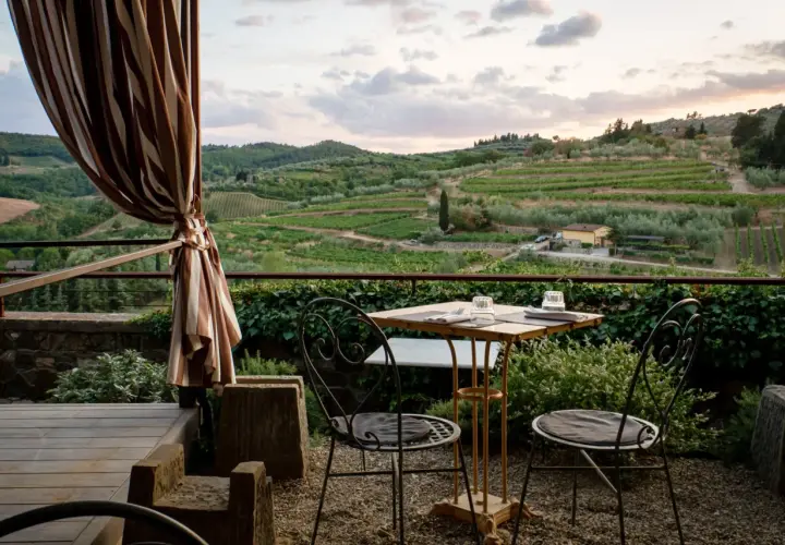 Terrasse d'agroturismo en Sicile avec vue sur les vignobles et les oliviers. Table dressée pour deux, prête pour un dîner paisible.