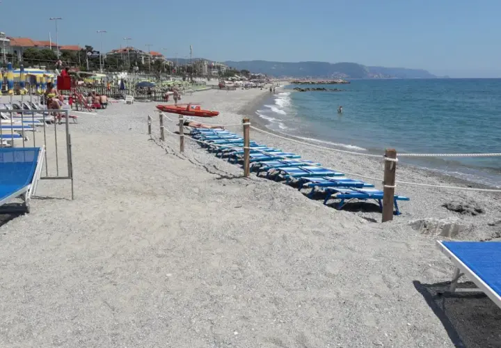 Plage de Loano, Italie, avec des chaises longues bleues alignées près de la mer Méditerranée.